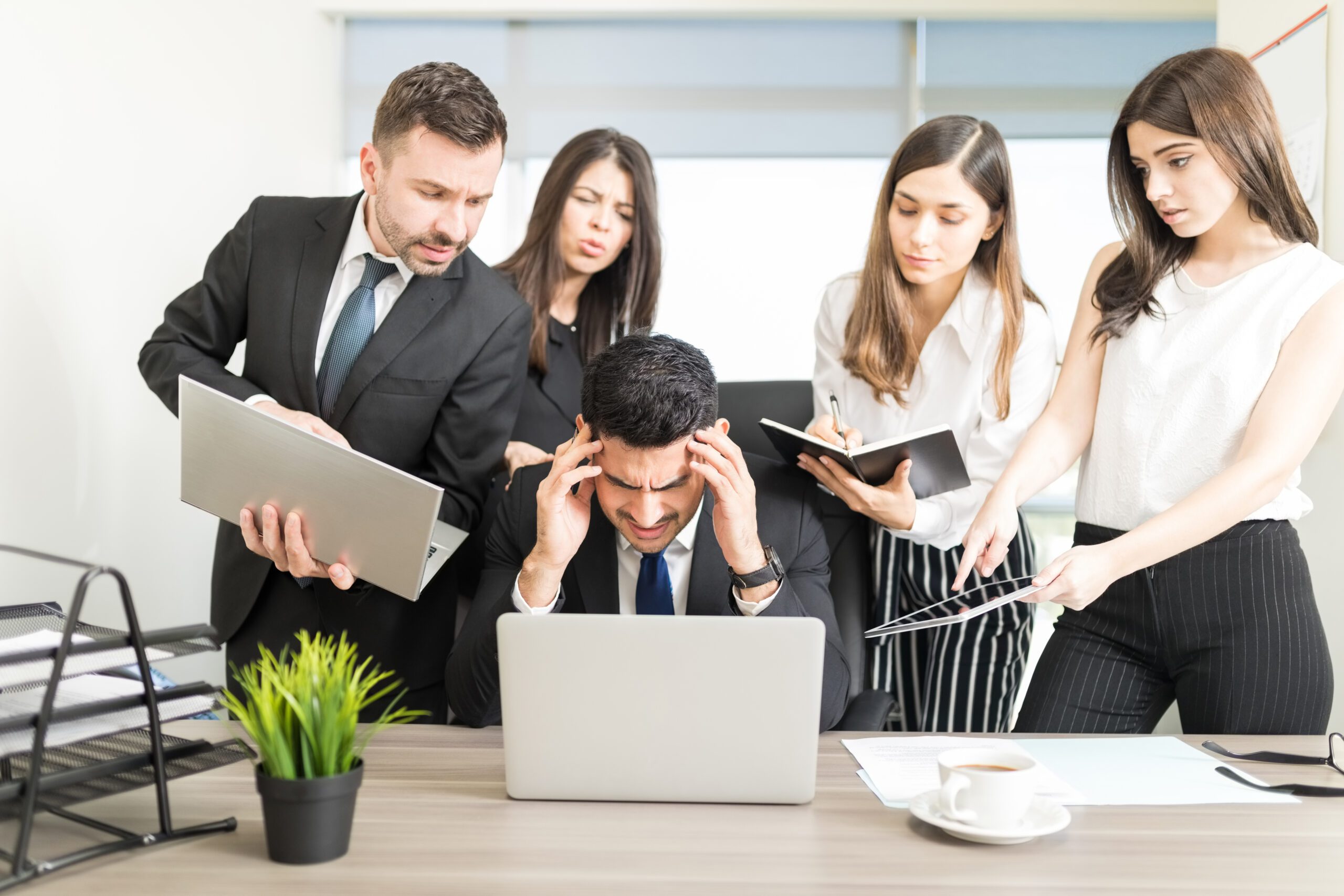 Stressed businessman unable to cope with too much work assigned by colleagues in office